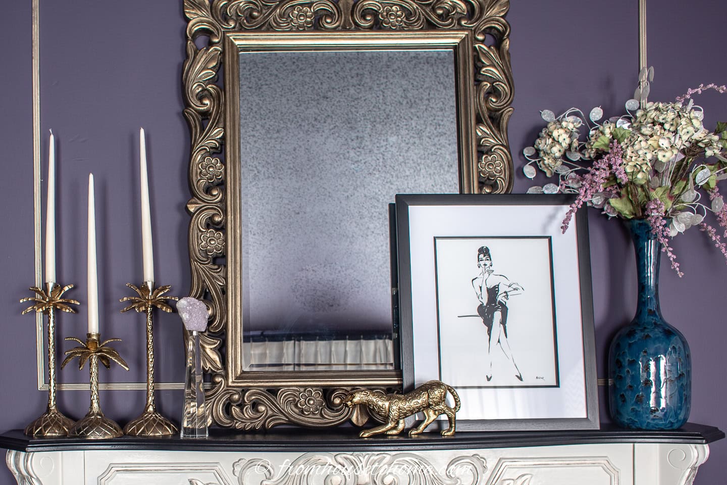 A close up of a gold-framed miror and gold accessories on a fireplace mantel