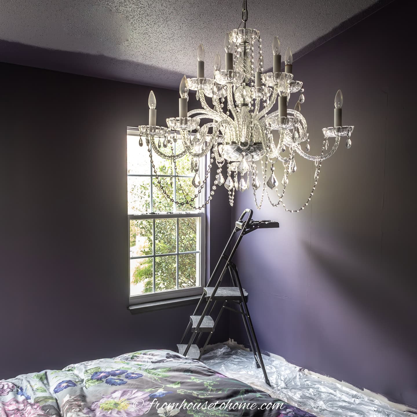 a chandelier in a bedroom being painted dark purple