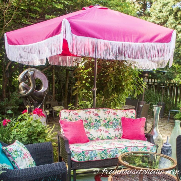 A deck with pink and blue furniture and a pink umbrella