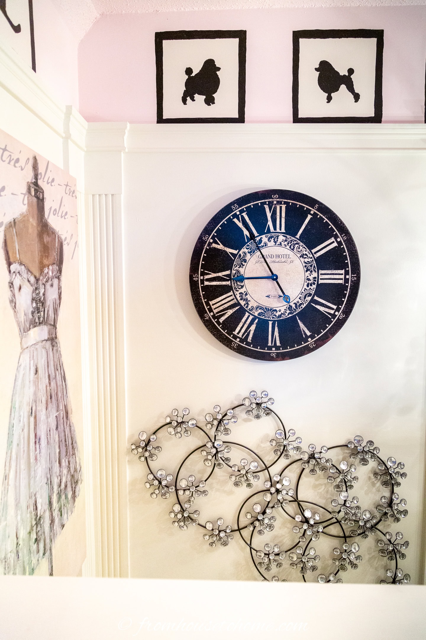 a gallery wall with wall sculptures and a large clock at the top of a stairwell