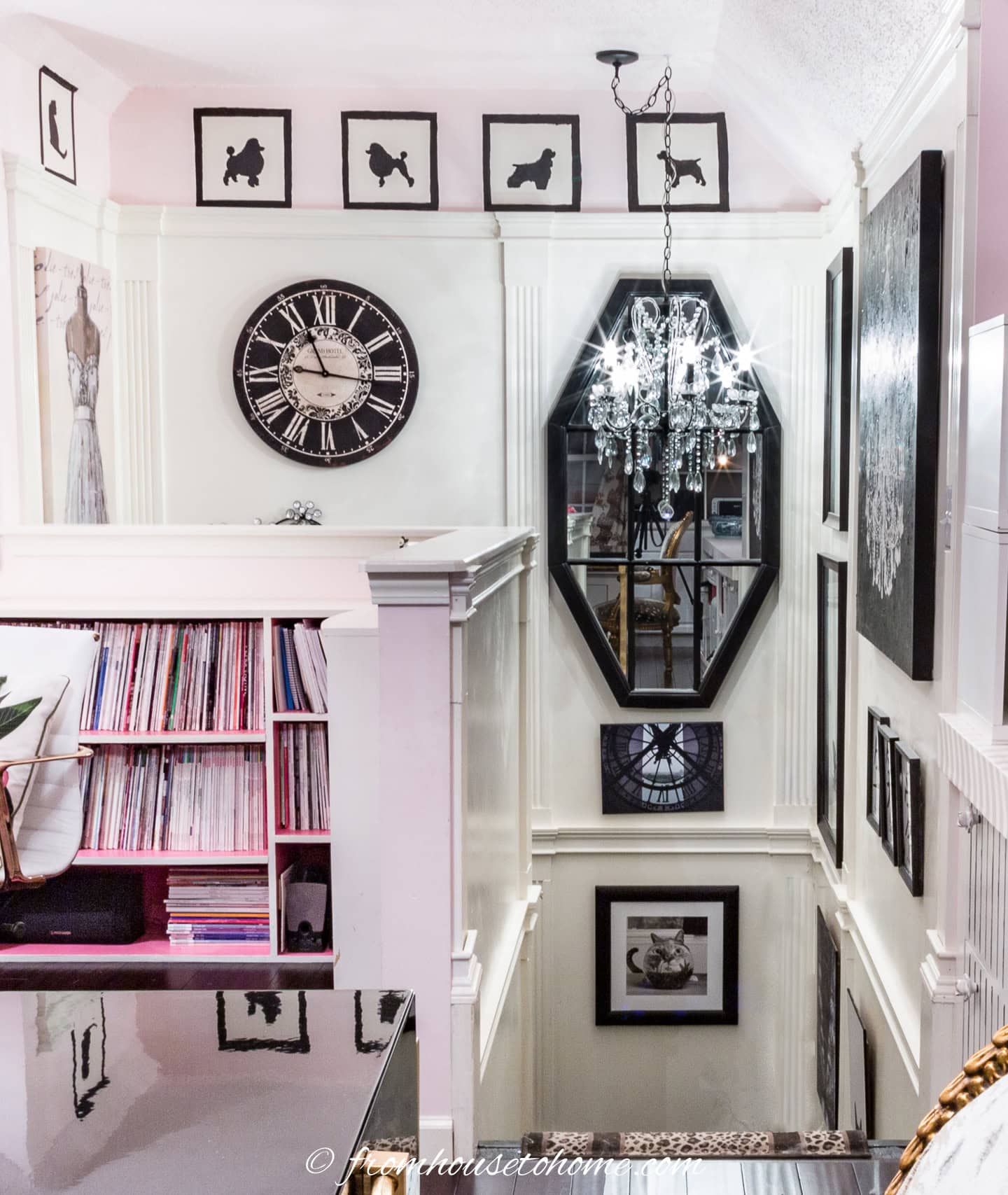 A stairwell gallery wall with a large mirror and a chandelier