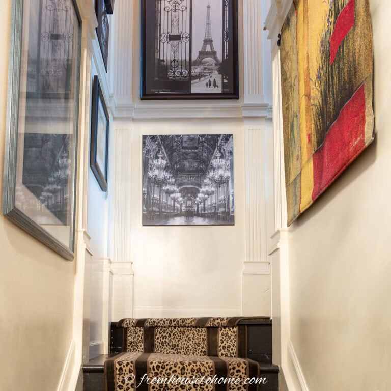 A leopard print stair runner on black stairs, and a gallery wall in a tall stairwell