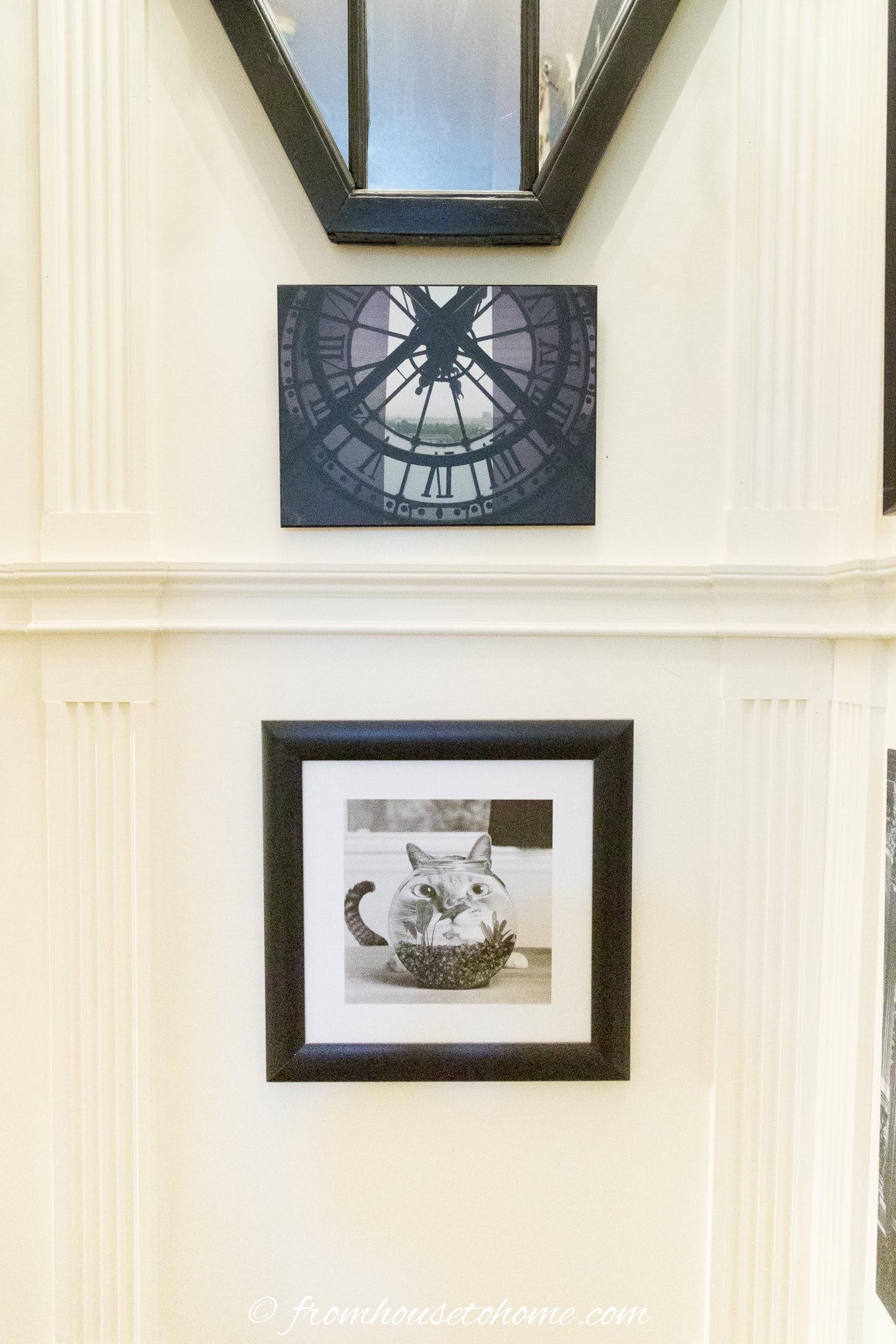 black and white pictures hung between moldings in a tall stairwell