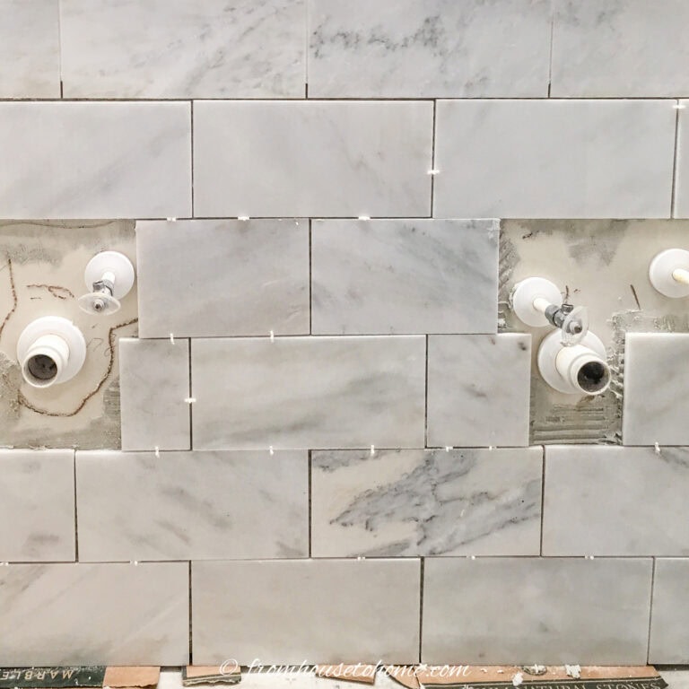 Marble tile on a bathroom wall with plumbing pipes