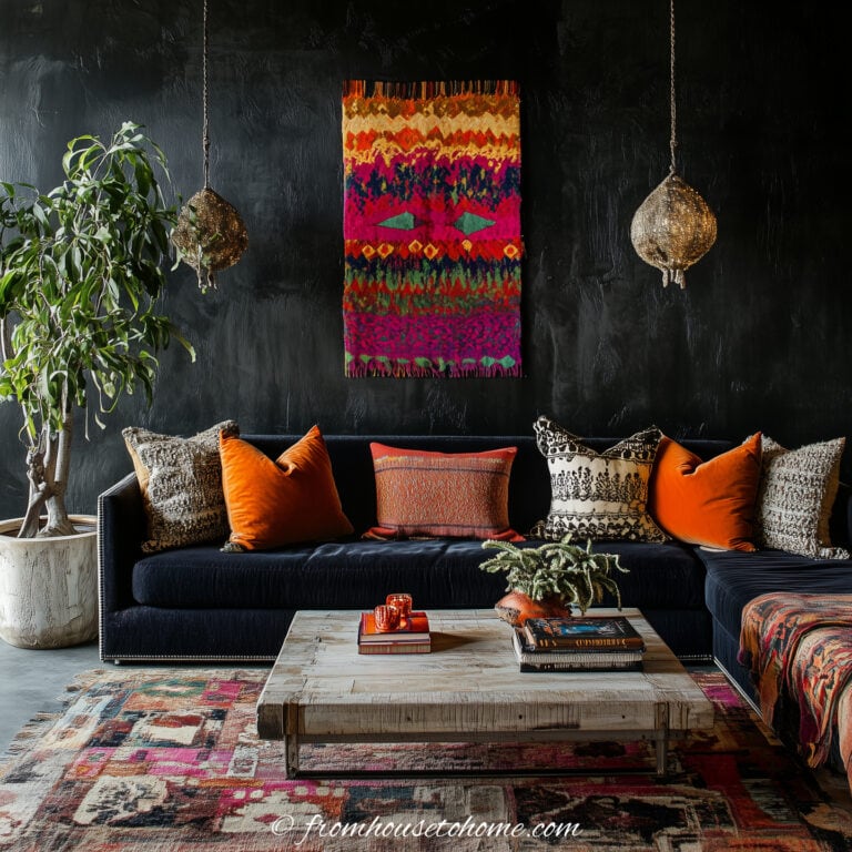 A bohemian style living room with a large house plant, tapestry on the wall, sectional sofa and brightly-colored area rug