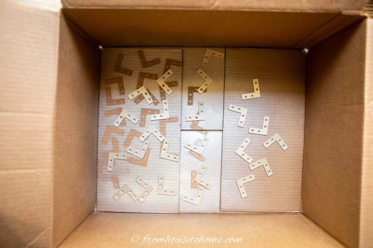 Gold spray painted angle brackets in a cardboard box