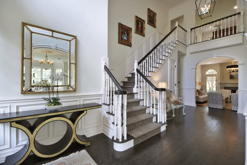 A gold-framed mirror over a gold and black art deco console table