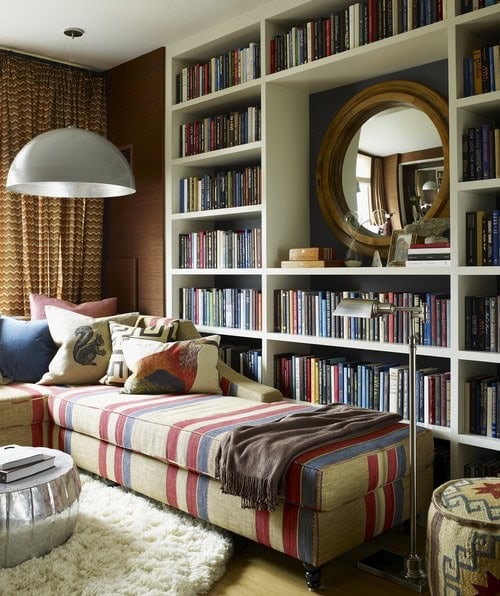 A mirror hung in the middle of a bookshelf