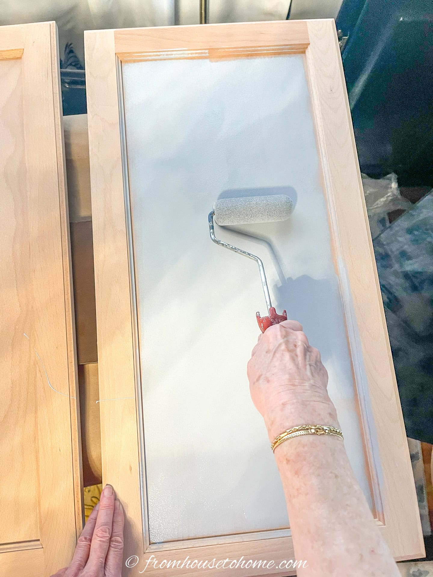 Primer being rolled onto an unfinished wood cabinet door