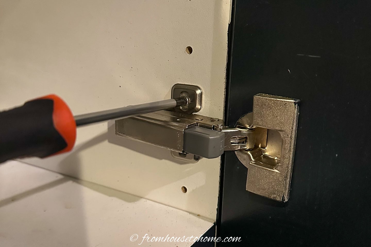 A painted kitchen cabinet door being attached to a melamine cabinet