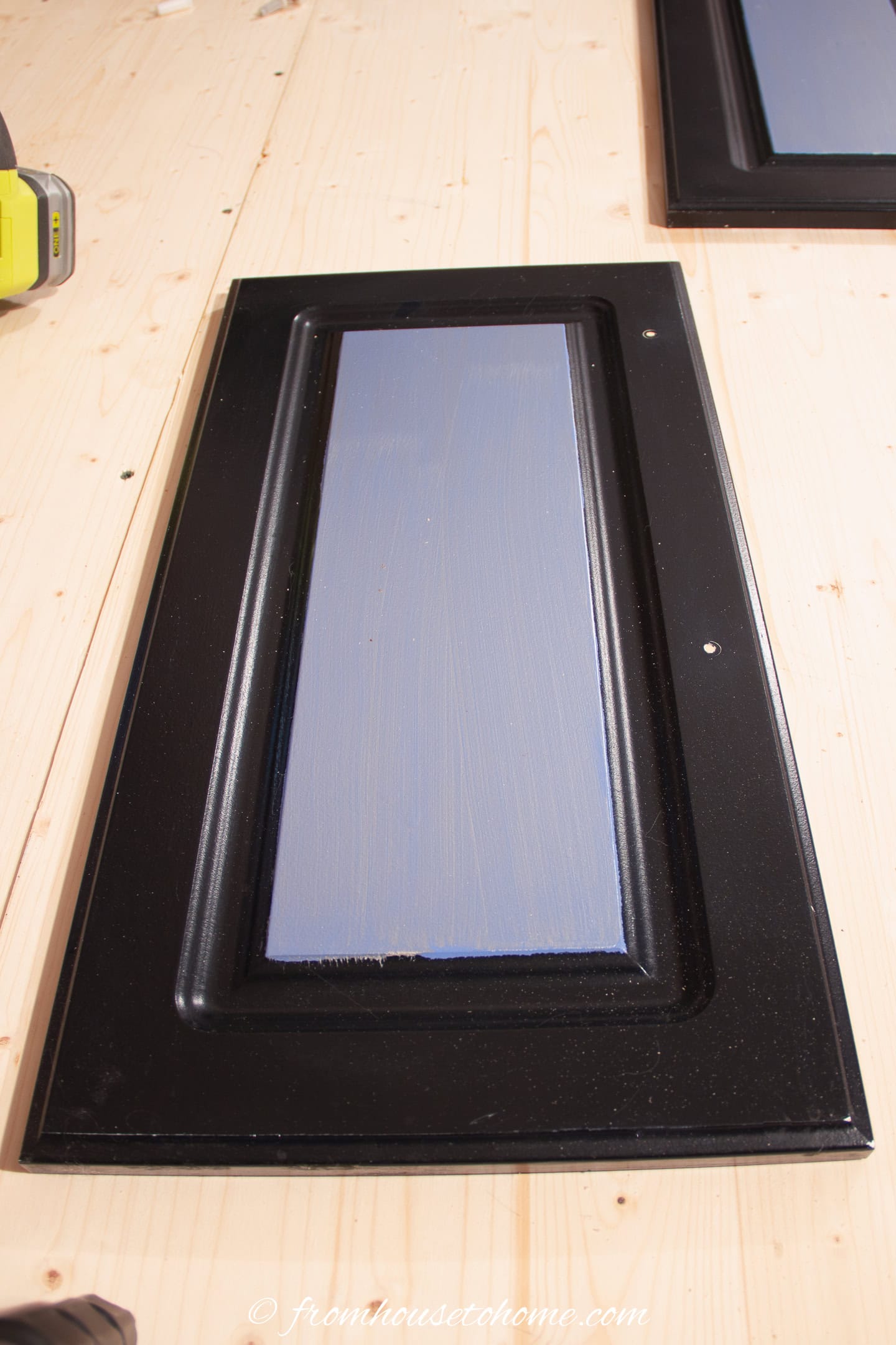 A kitchen cabinet door with holes drilled for the new handles