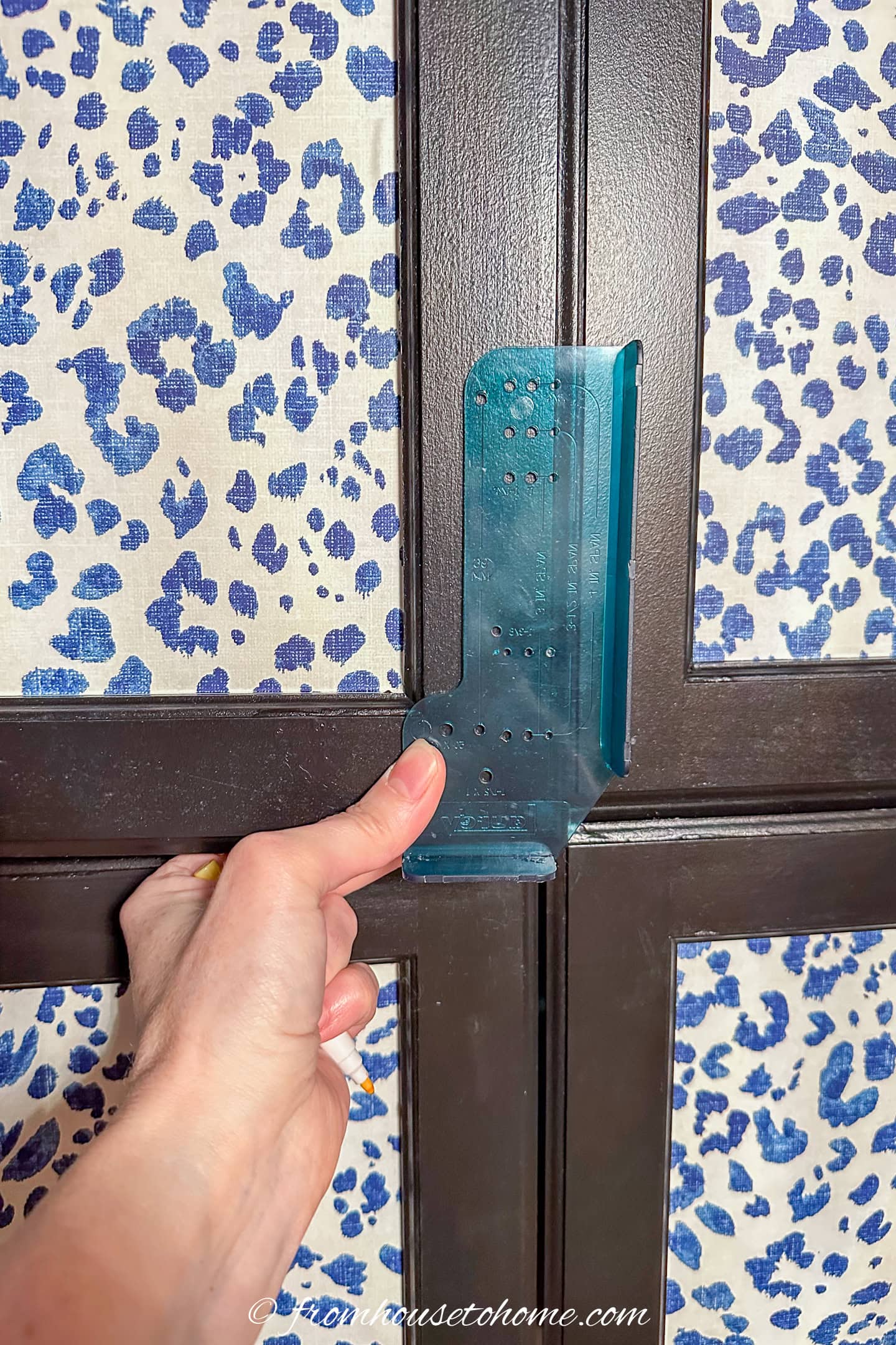 A template being used to mark knob locations on kitchen cabinet doors