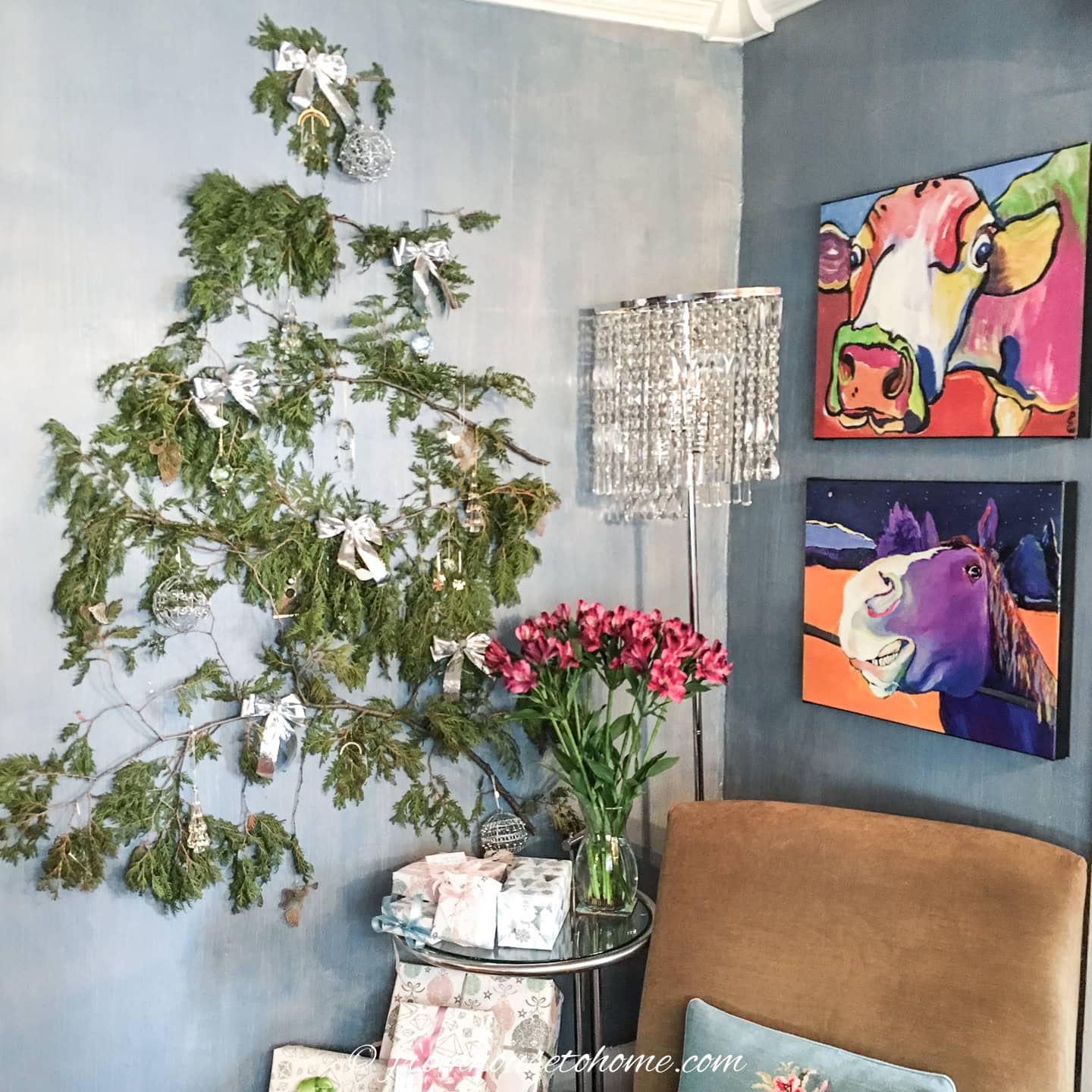 A wall Christmas tree beside a chair and table in a living room