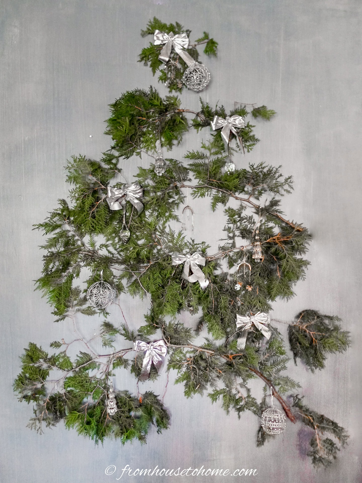 A DIY wall Christmas tree decorated with silver bows and ornaments