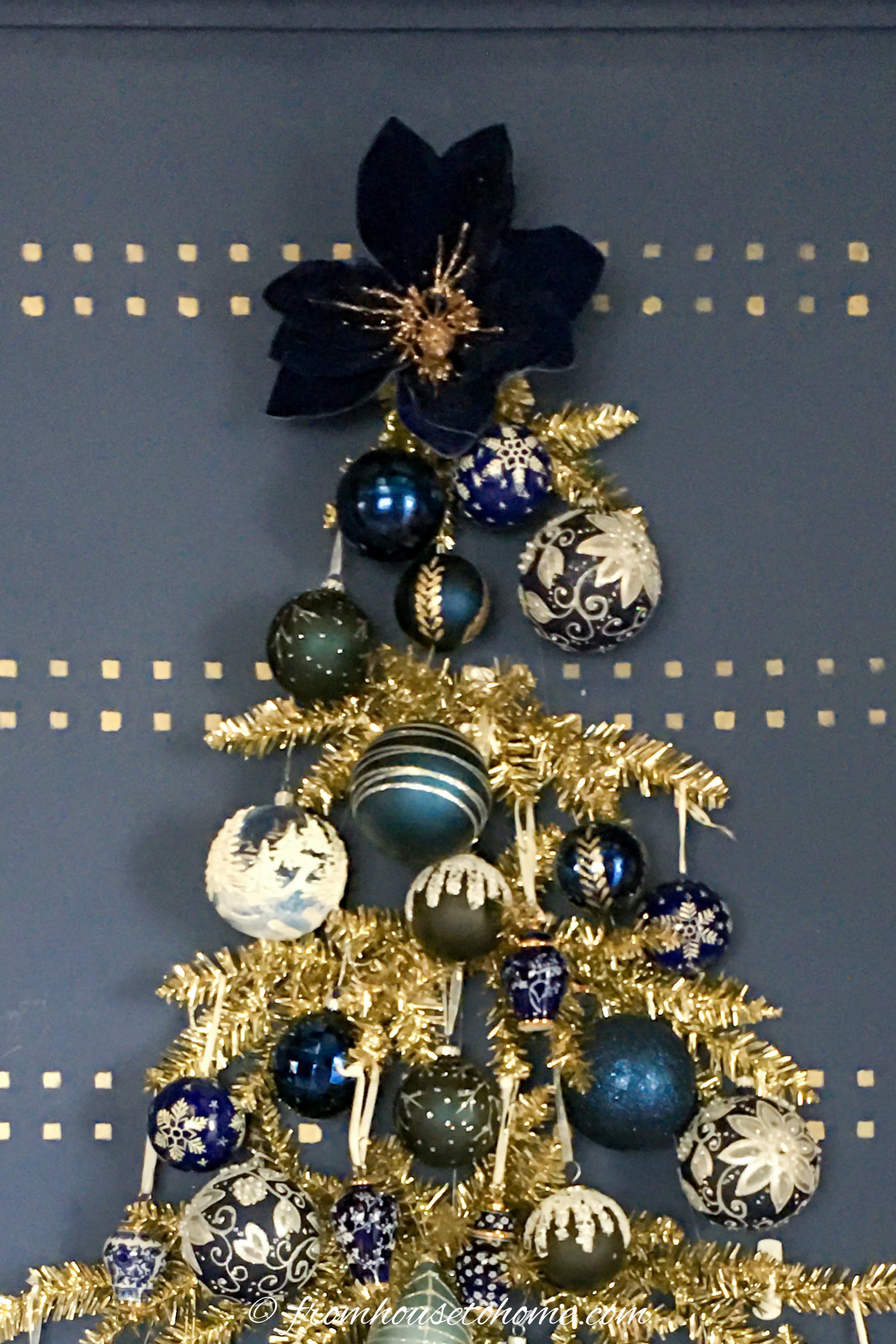 The top of a wall Christmas tree with a blue poinsettia tree topper