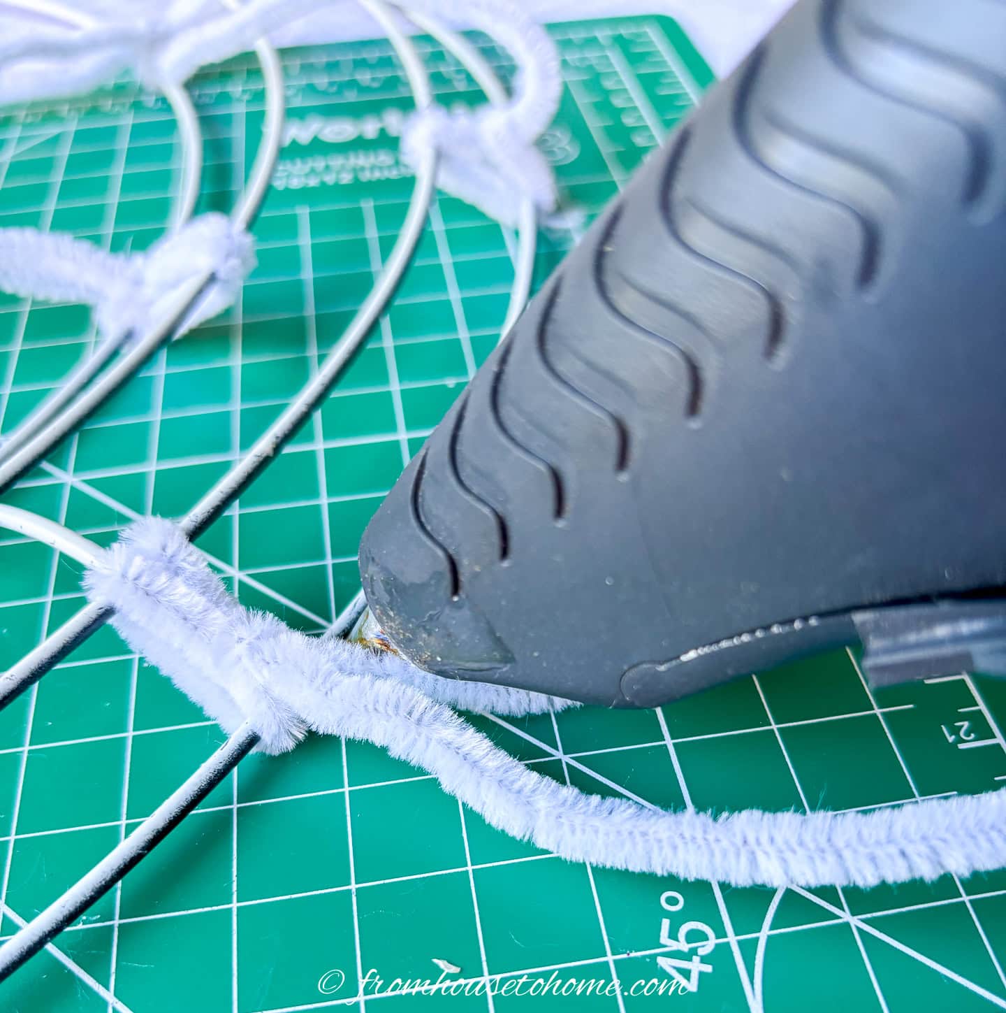 pipe cleaner being hot glued to the wire wreath form