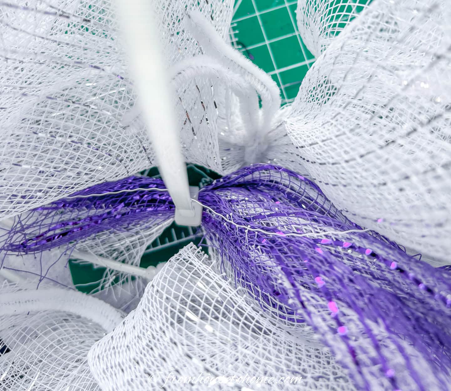 the start of the purple deco mesh being attached to a wreath form with white deco mesh on it