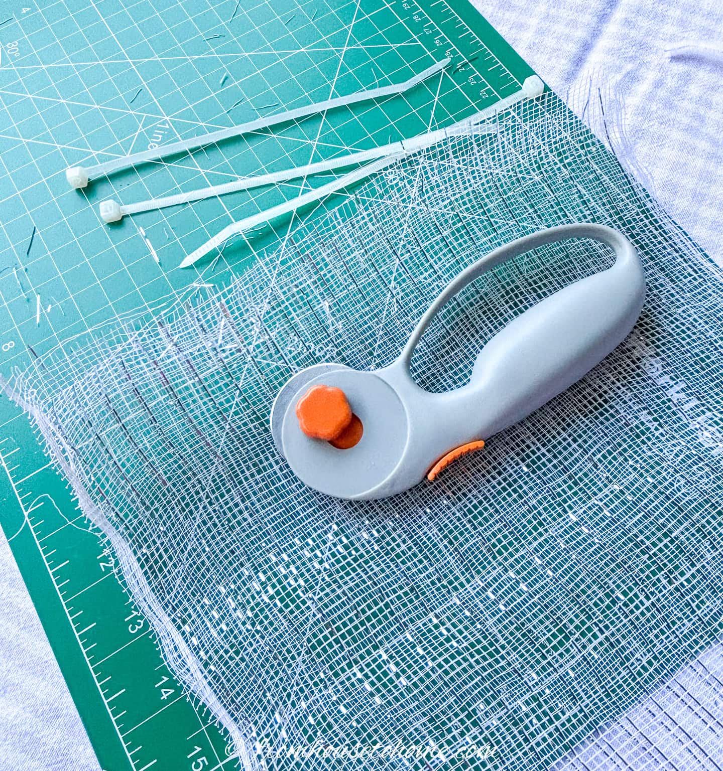 zip ties, cutting wheel, and deco mesh on a cutting mat