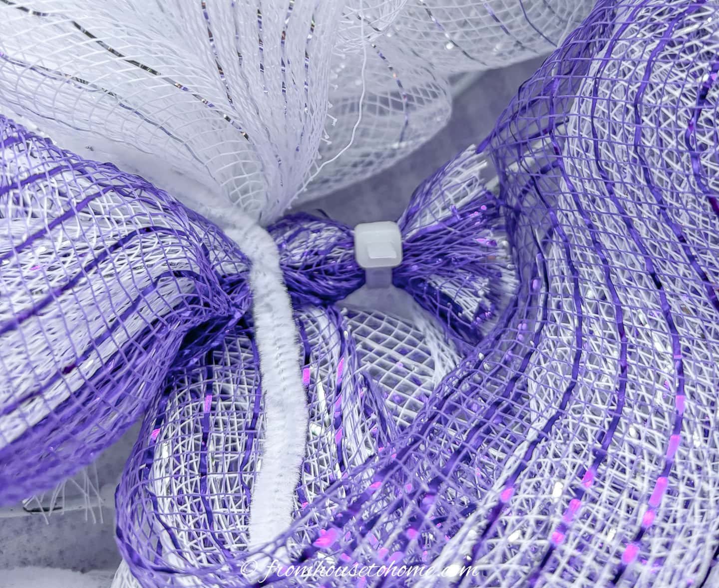 the end of the purple deco mesh zip tied to the wreath form and trimmed