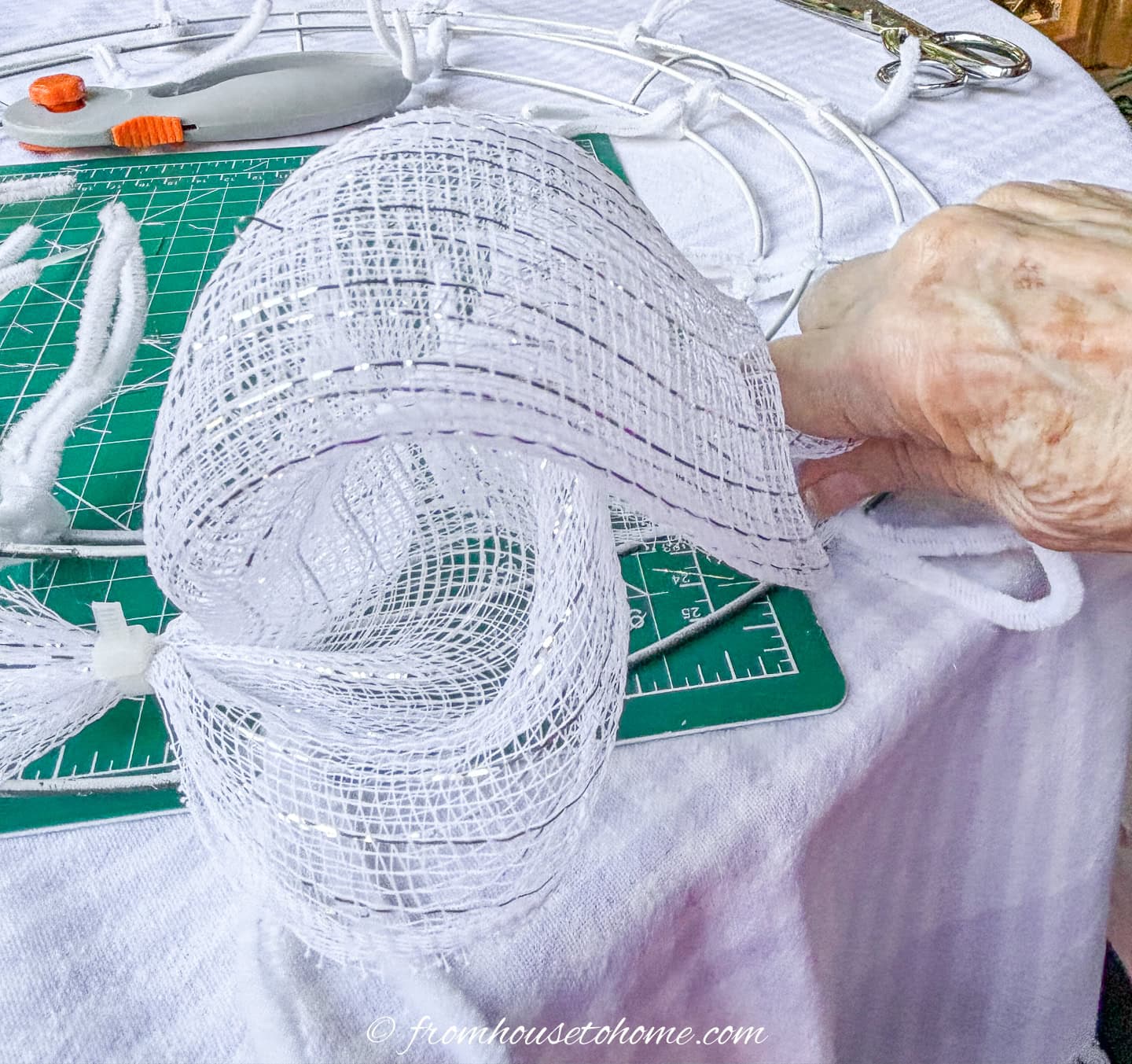 deco mesh poof being attached to the wreath form with a pipe cleaner