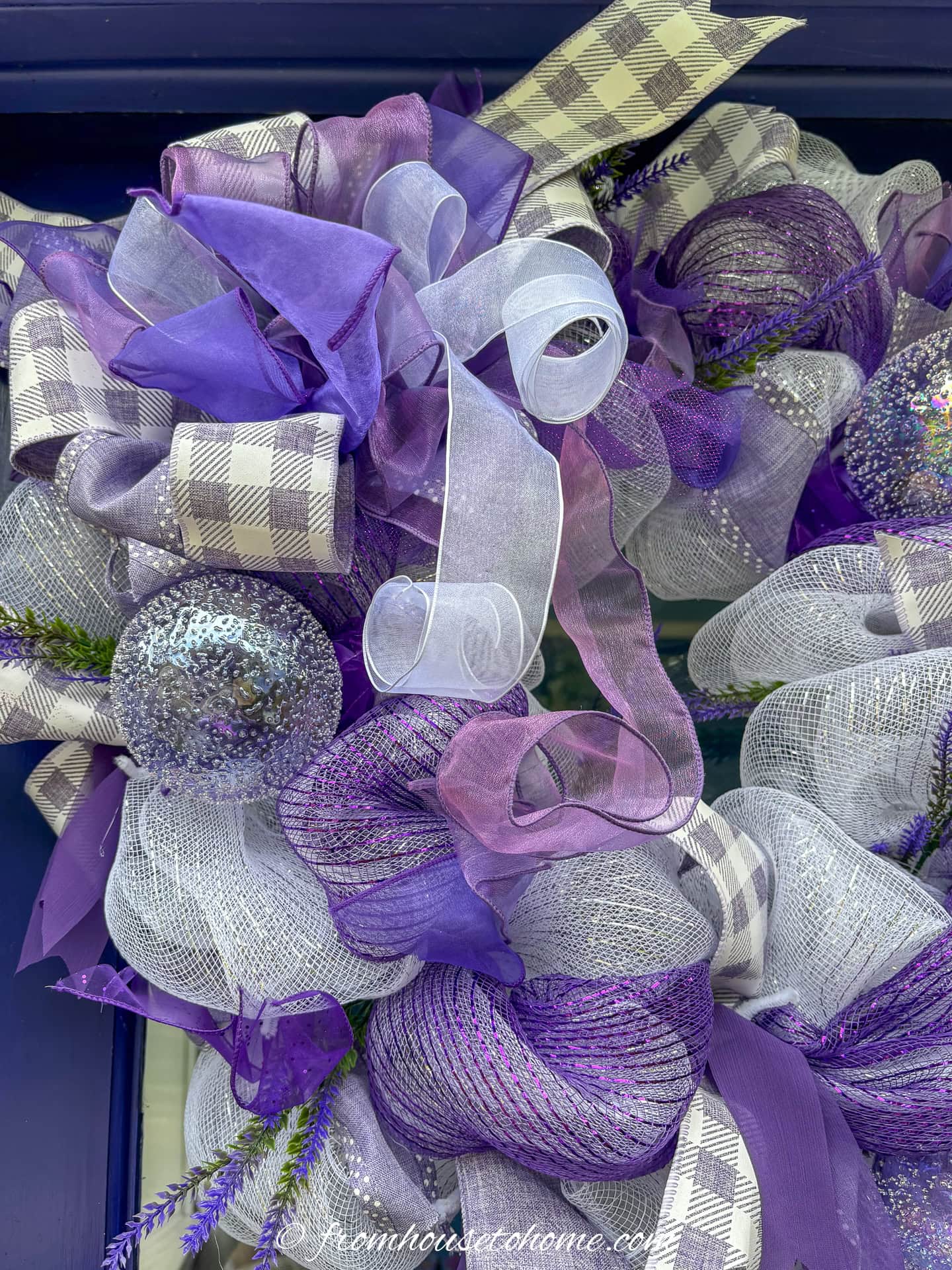 close up picture of the glass ball ornaments on a purple and white deco mesh Christmas wreath