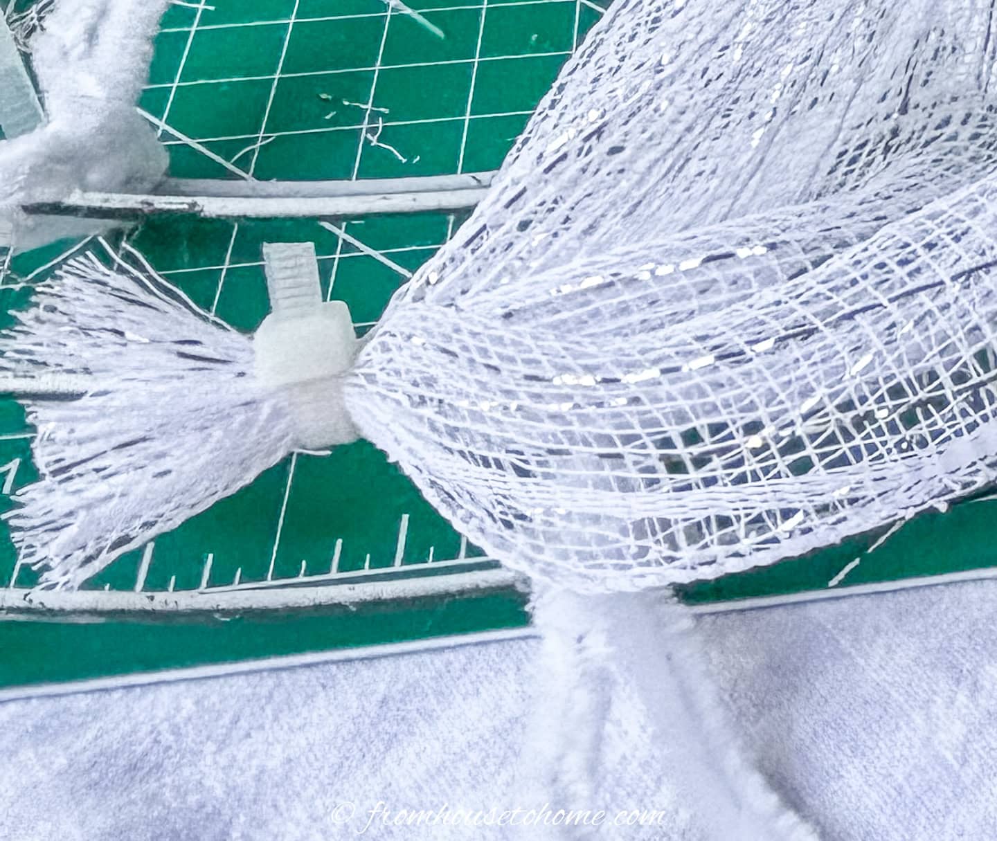 a zip tie with its tail cut off attaching deco mesh to a wreath form