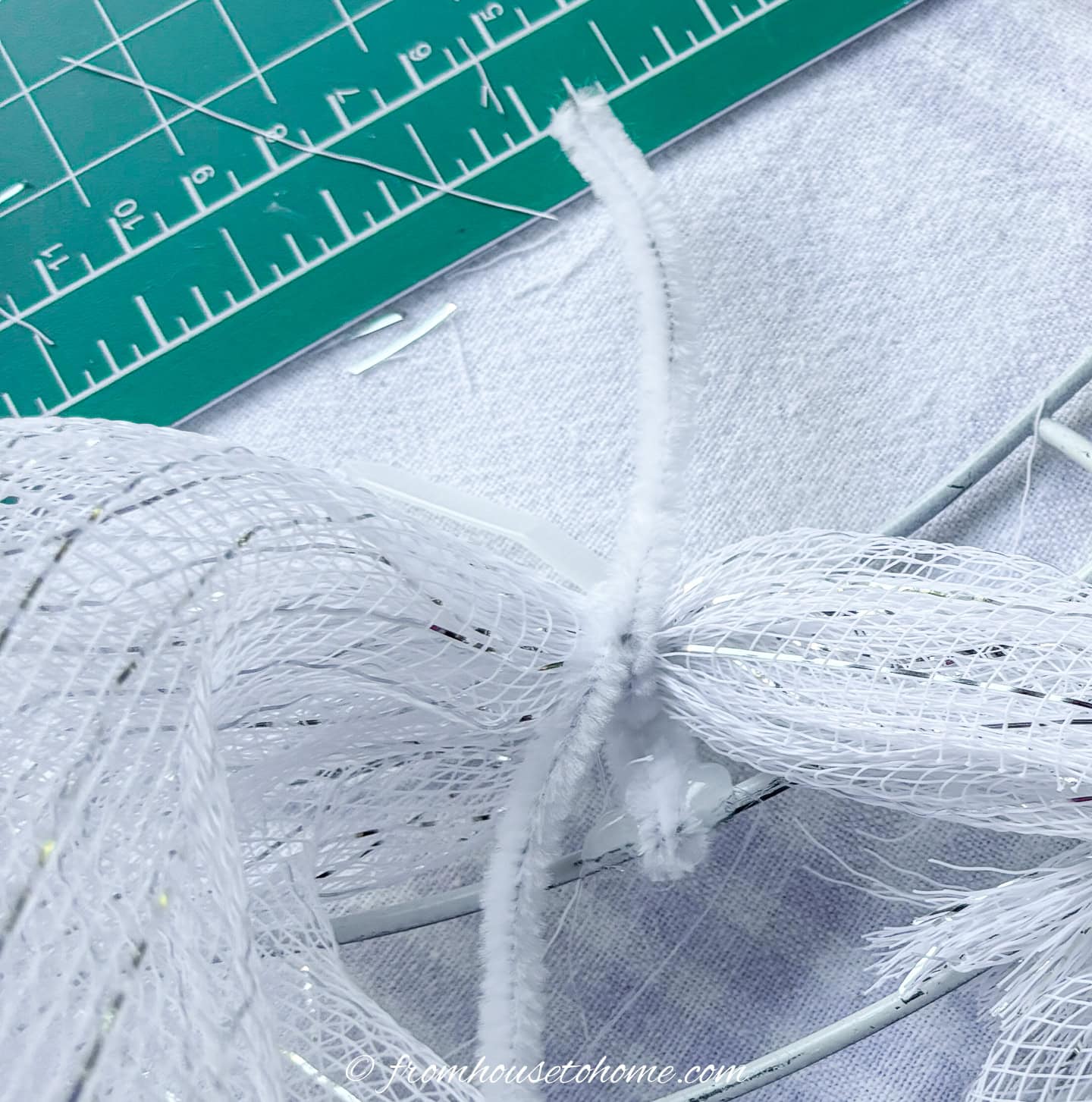 close up of a pipe cleaner attaching deco mesh to the wreath form