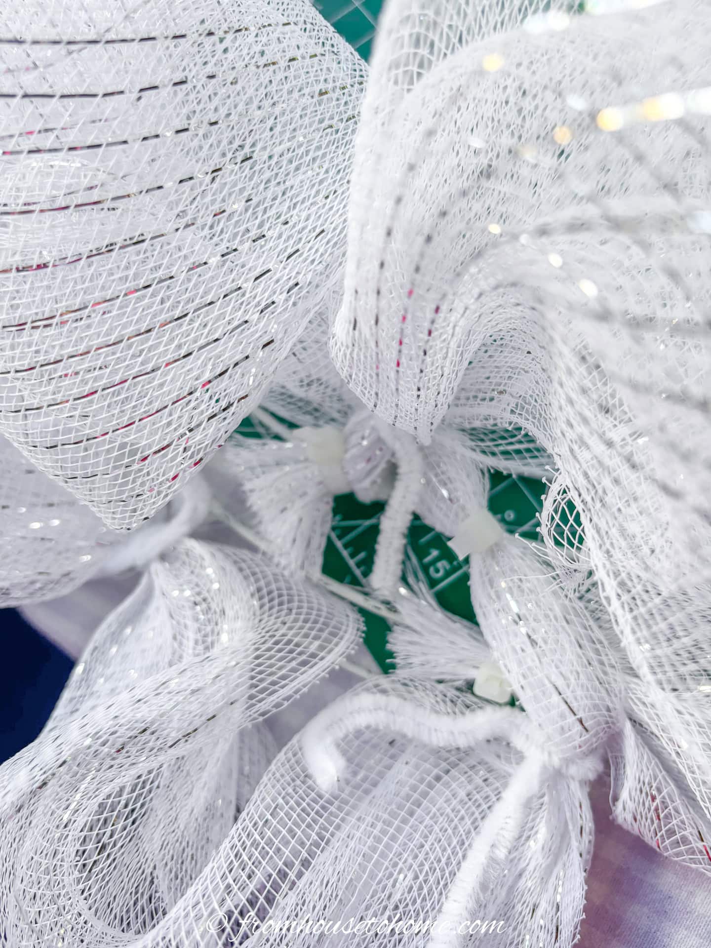the end of the white mesh being attached to the wire wreath form with a zip tie