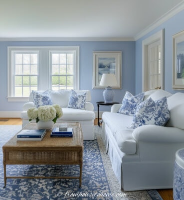 a blue and white living room with two sofas placed in an L-shape