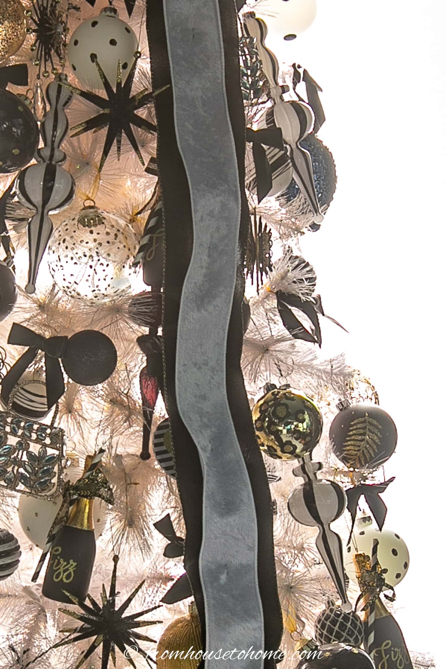 a black and white ribbon running down the front of a white Christmas tree with black decorations