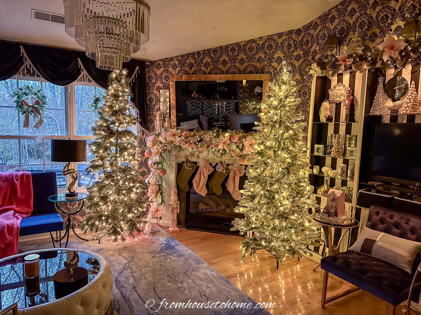 A living room decorated for Christmas with pink and gold Bridgerton-inspired decorations and gold damask wall covering