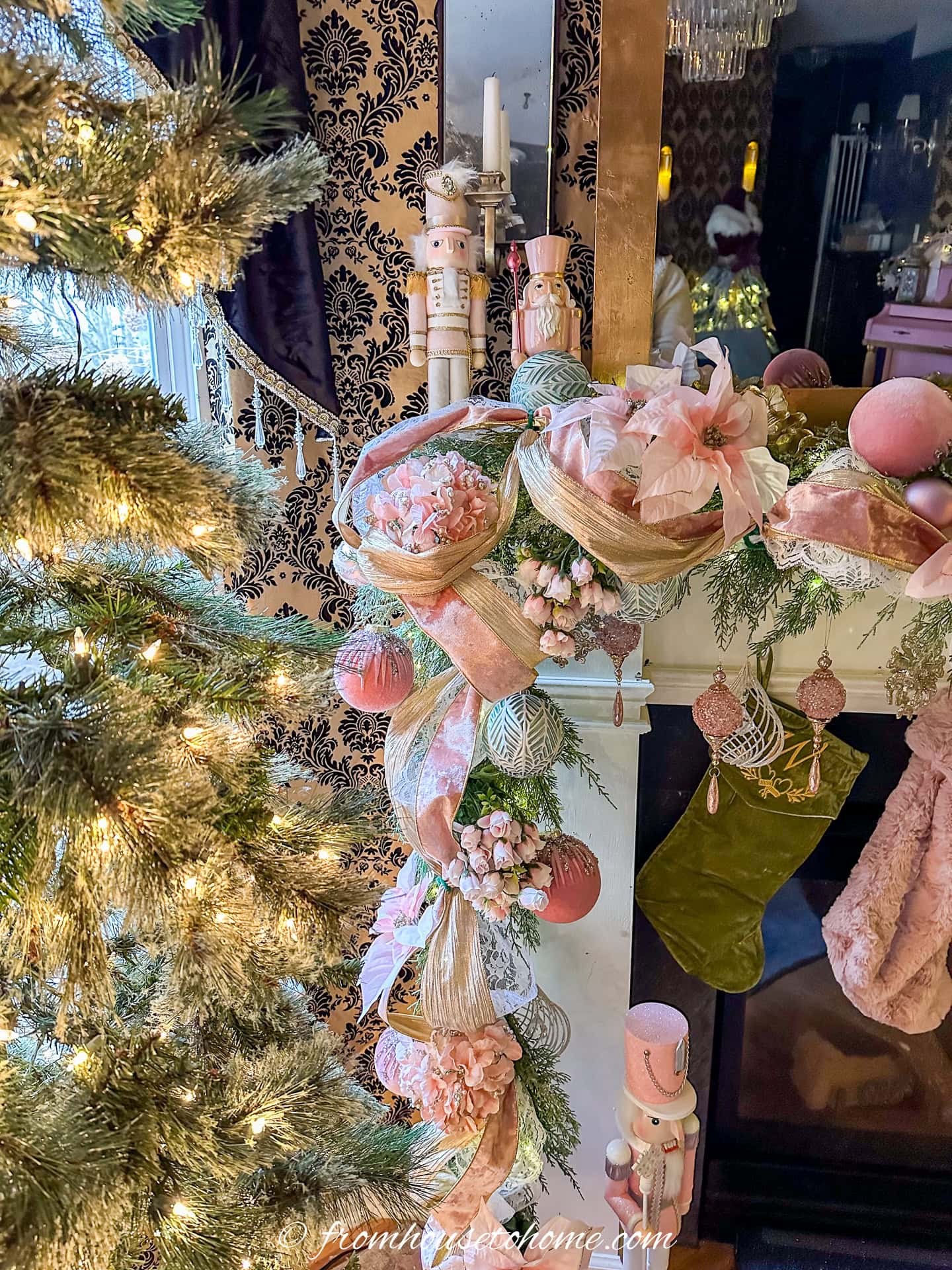 The corner of a pink garland over a fireplace mantel with pink nutcrackers in the corner