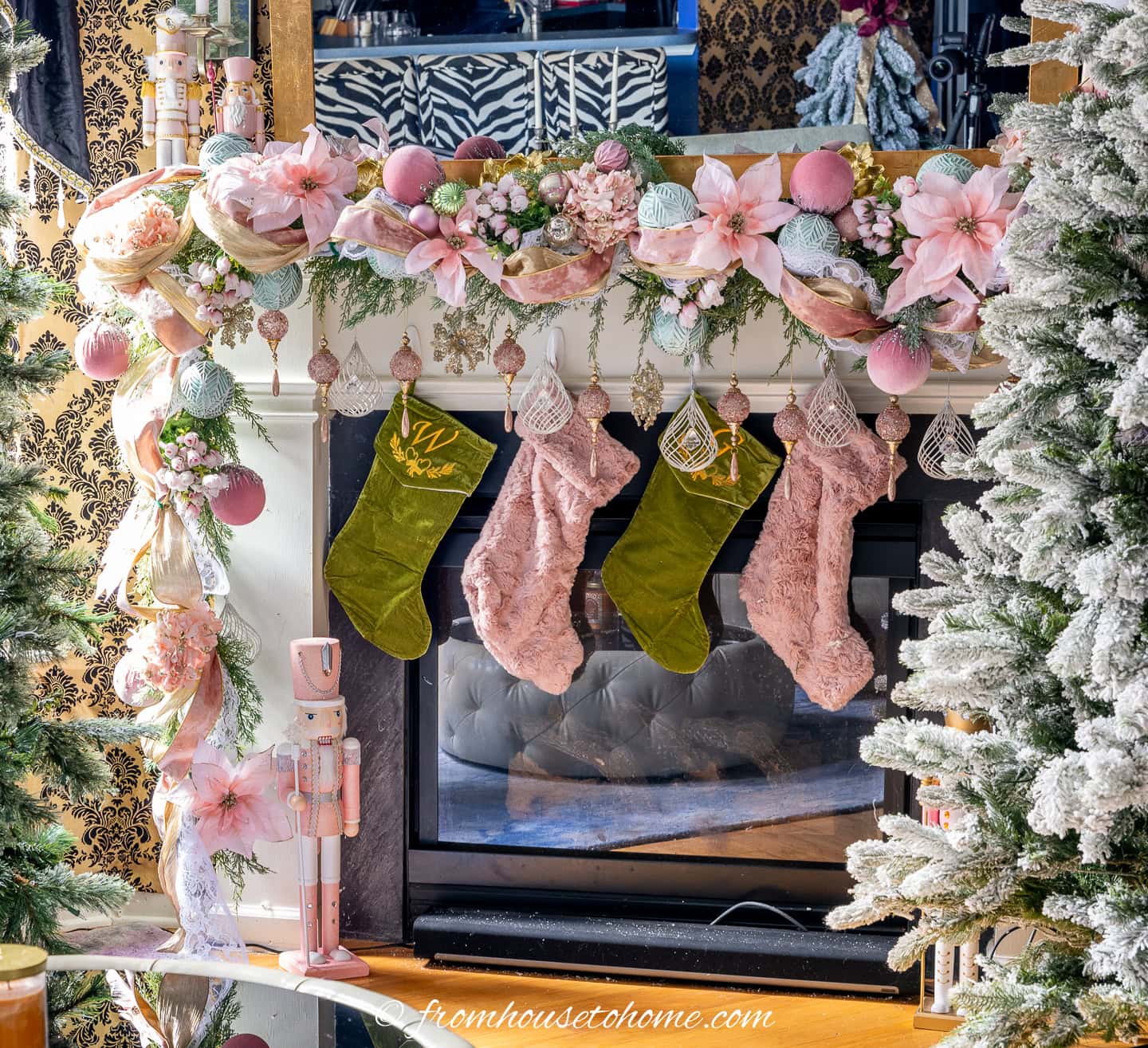 A pink and gold garland on a fireplace mantel with pink and green stockings