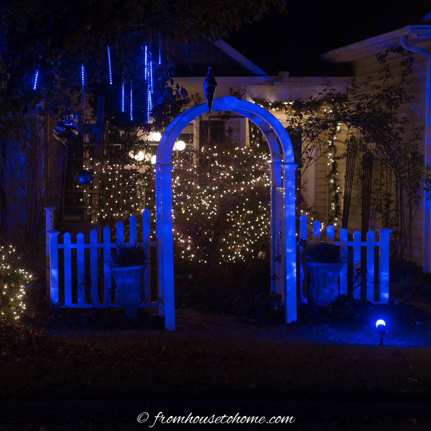 front yard arbor lit with blue flood lights and white string lights for Christmas