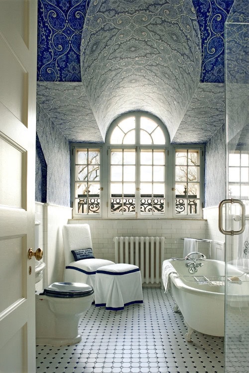 A white bathroom with two different wallpaper patterns on the ceiling