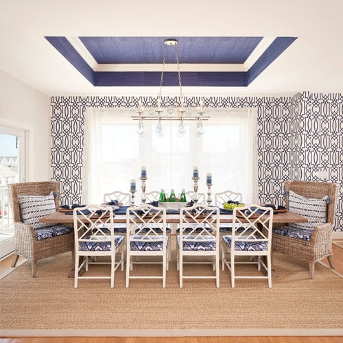 A casual dining room with dark blue wallpaper in a tray ceiling
