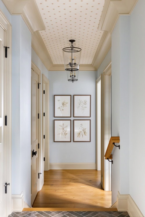 A coastal blue hallway with subtle white and gold wallpaper on the ceiling
