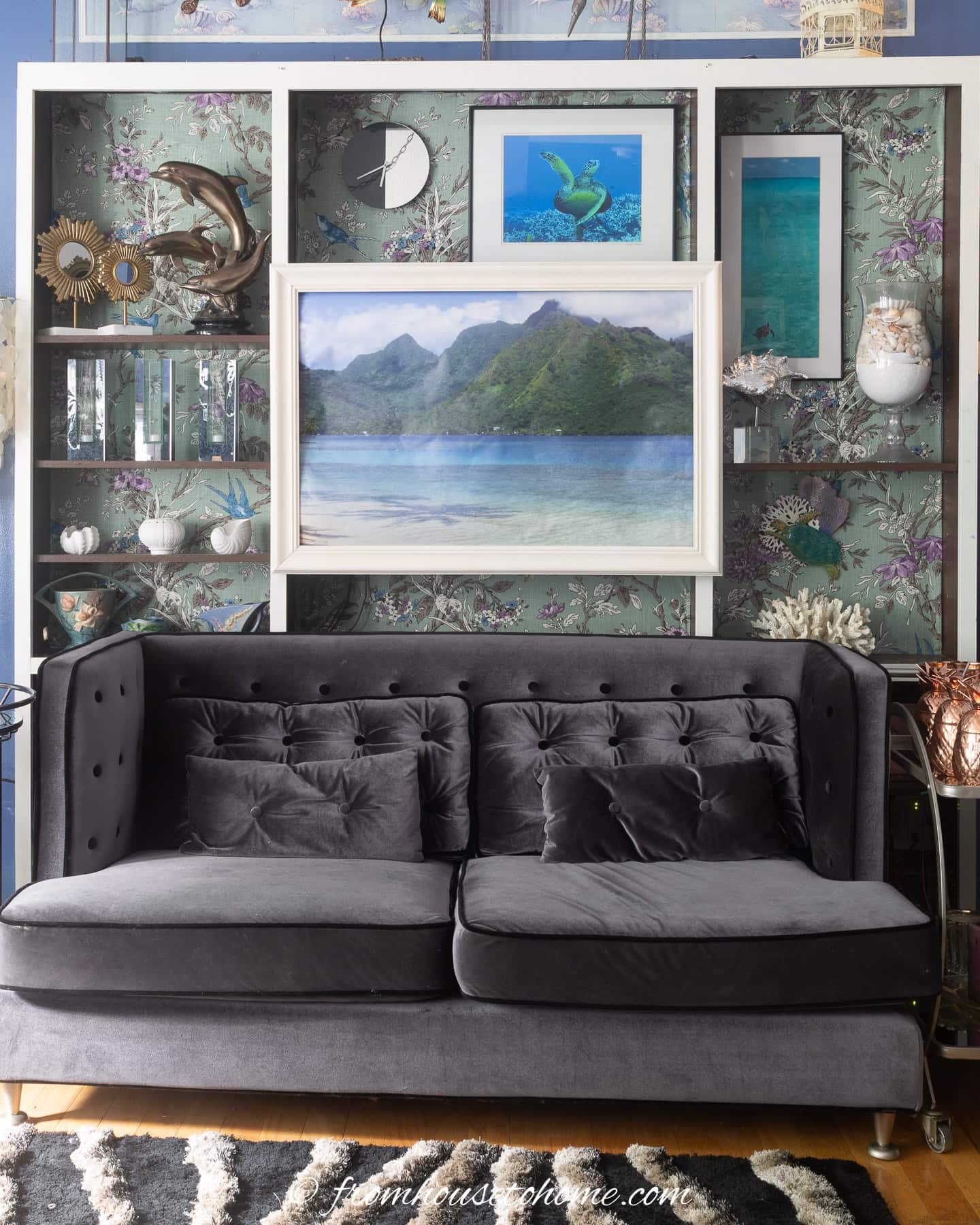 A pull down picture and frame covering a TV on a bookshelf behind a sofa