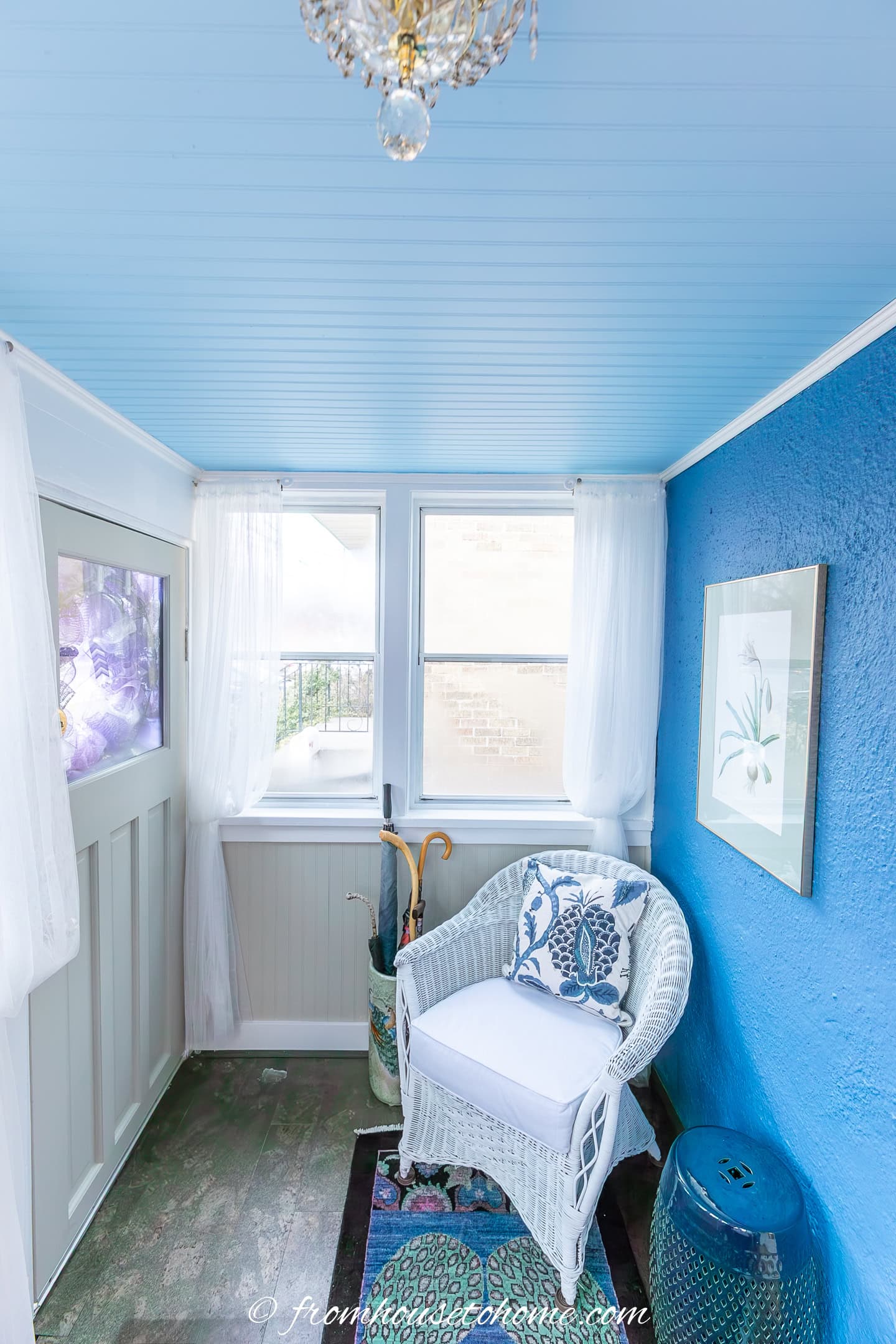 A small sunroom with a beadboard ceiling that has been painted light blue