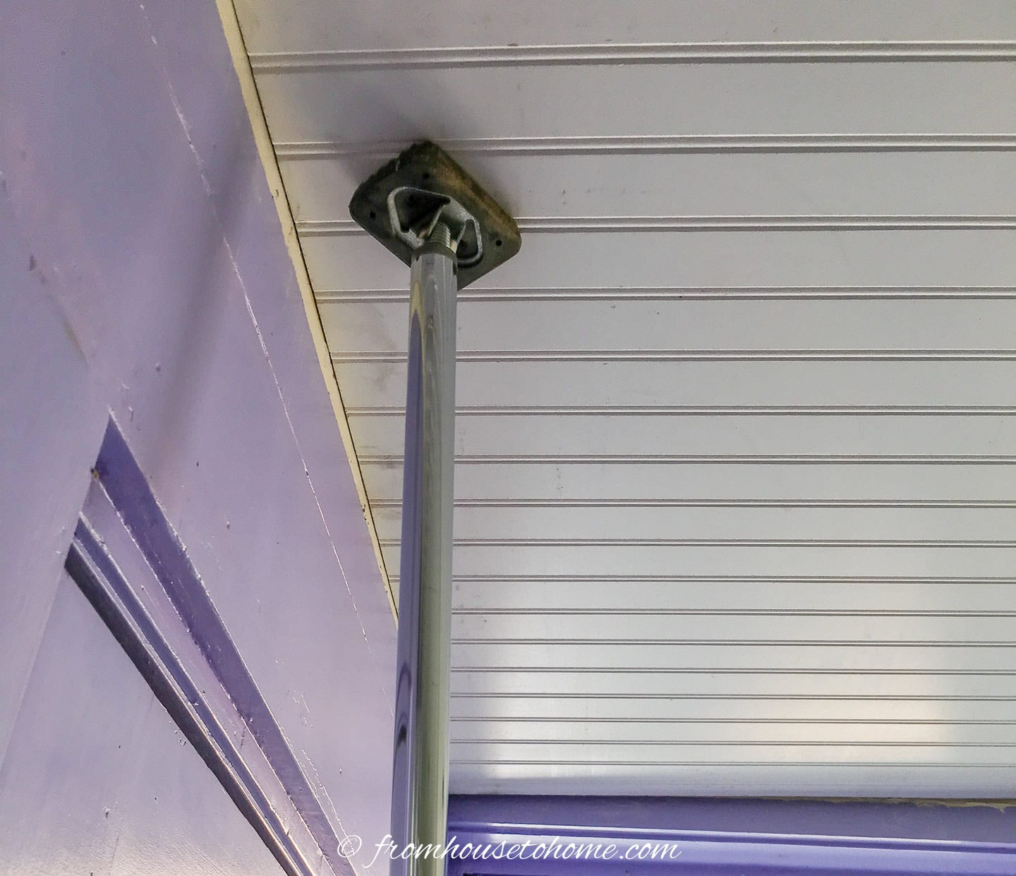 Close up of beadboard being held up to the ceiling with a support pole