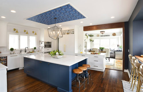 A blue and white kitchen with blue wallpaper on the ceiling over the island