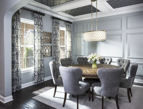 A gray dining room with a round table, white beams and black wallpaper on the ceiling
