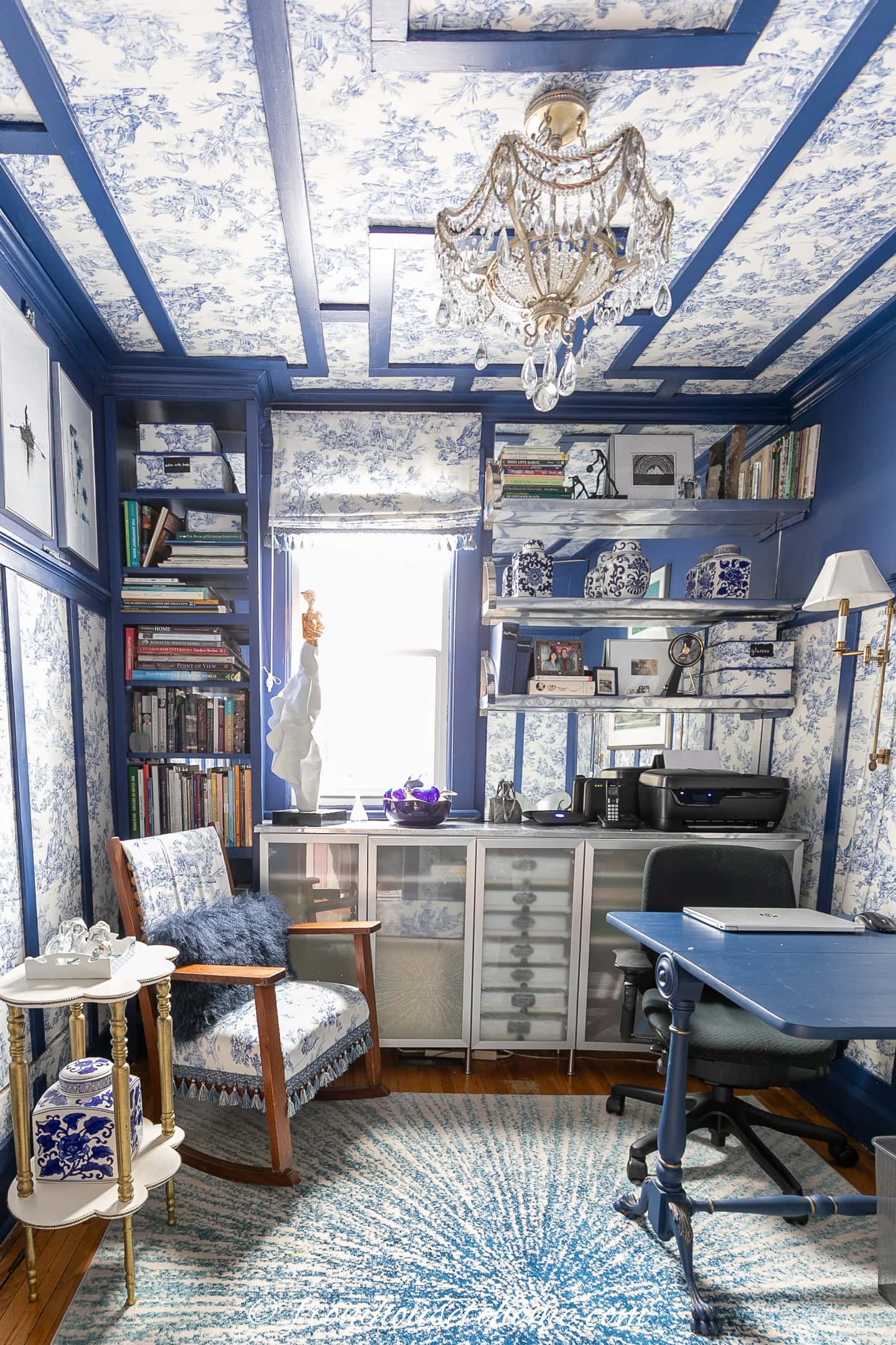 A smal home office with blue moldings and blue and white toile wallpaper on the ceiling