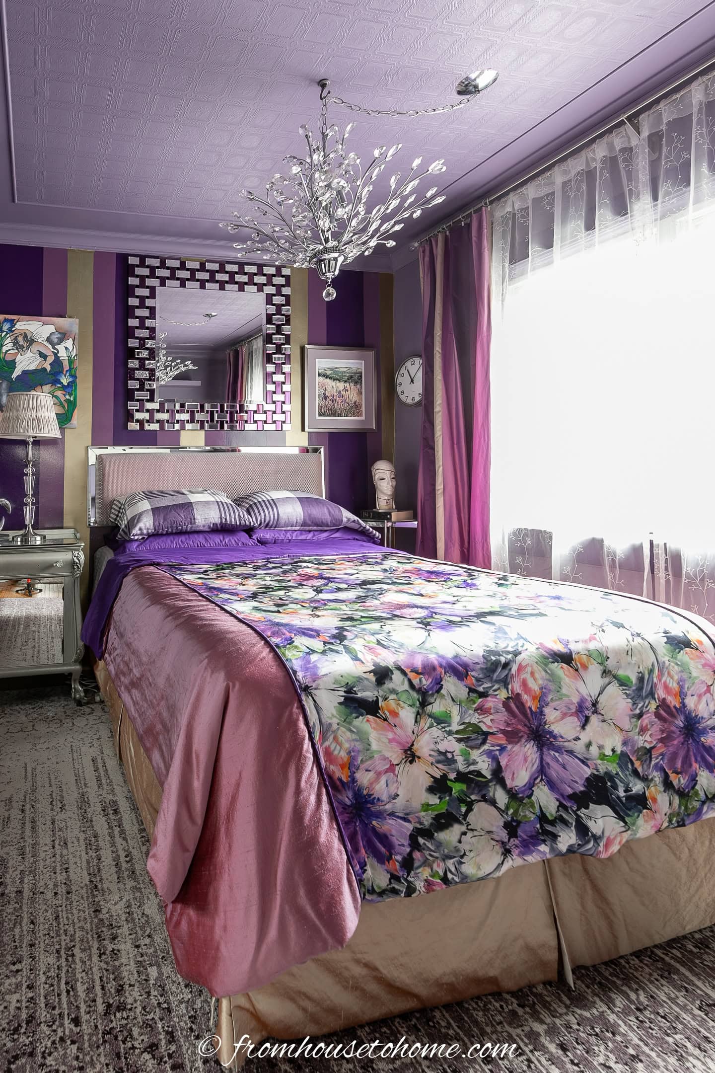 A small bedroom with patterned wallpaper on the ceiling that has been painted purple