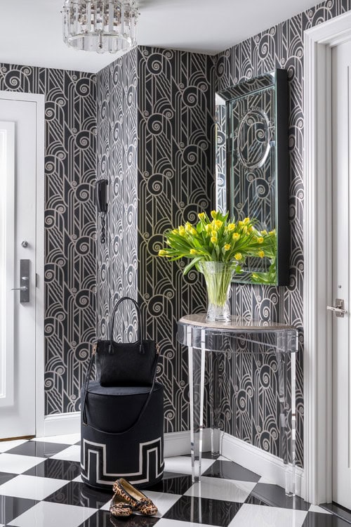 A hallway with black and white Art Deco wallpaper and checkered tile floor