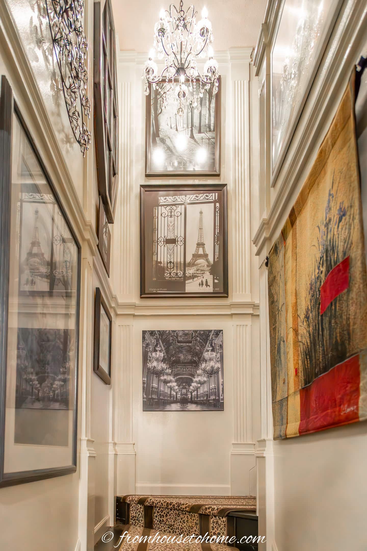 A tall stairway with fluted moldings, black and white pictures and a leopard print runner