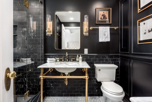 An Art Deco bathroom with black marble tile and gold accents