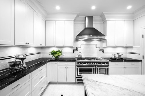 A black and white kitchen with Art Deco geometric lines in the backsplash