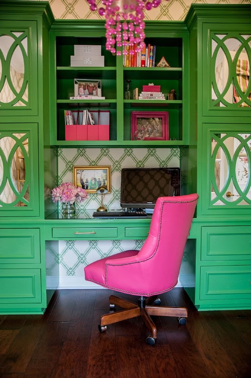 A green library wall with pink accents and green and white wallpaper in the background