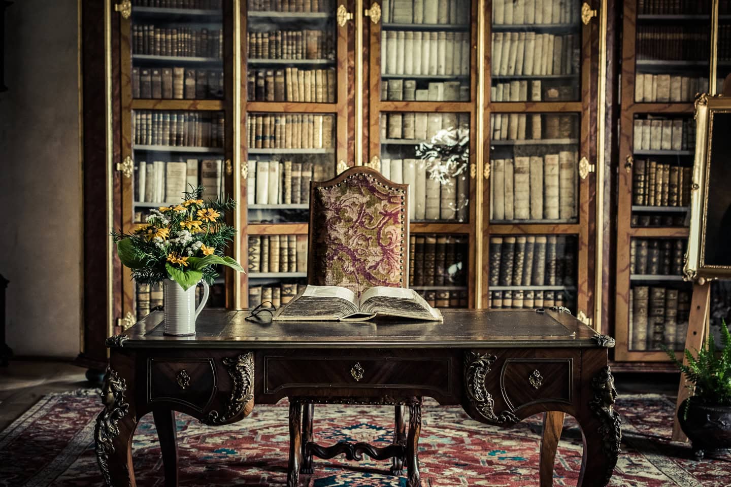 A desk in front of a library wall bookshelf with doors